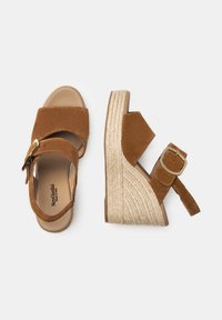 Brown suede wedge sandals with dual straps, a gold buckle, and a textured espadrille-style platform.