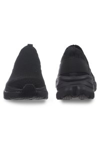 Schwarze Sportschuhe mit einem gestrickten Obermaterial, im Slip-On-Design und Gummisohlen. Auffällige Details sind strukturierte Akzente und eine Zuglasche.