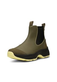 Botas de goma de tobillo en color verde oliva con paneles laterales elásticos, puntera texturizada en marrón, tirador y suela de tracción amarilla.