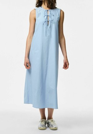 Robe midi bleu clair sans manches avec un détail à lacets à l'avant portée avec des baskets argentées sur une personne debout.