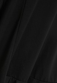 Schwarzes Kleid mit glatter Textur, ausgestattet mit einem taillierten Oberteil und einem ausgestellten Rock. Der Stoff wirkt leicht und leicht dehnbar.