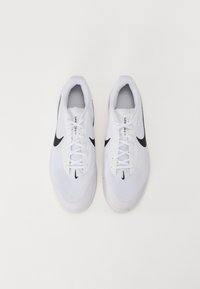 Pár bílých běžeckých bot Nike s černými logy swoosh, bílými tkaničkami a větranými síťovinovými svršky zobrazený z vrchu na bílém pozadí.