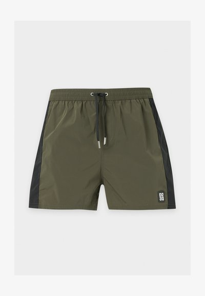 Short de bain vert olive avec panneaux latéraux noirs, taille élastique, cordon noir et petit écusson carré avec le logo sur la jambe gauche.
