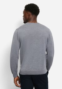 Maglione grigio con lavorazione a maglia testurizzata, scollo rotondo e polsini a coste. Presenta un design sobrio e un'etichetta laterale sull'orlo. Vestibilità regolare.