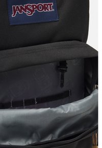 Črn nahrbtnik JanSport z prostornim notranjim delom v sivi podlogi, več shranjevalnimi žepi in zadrgo z logotipno nalepko.