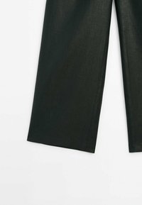 Pantalon à jambes larges vert foncé montré de la mi-cuisse à la cheville sur fond blanc, mettant en valeur la texture du tissu et les coutures nettes de l'ourlet.