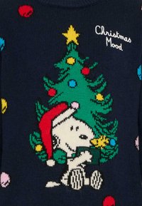Maglione blu navy con un design natalizio che presenta un albero, ornamenti colorati e un cane da cartone animato con un cappello rosso, con il testo "Christmas Mood".
