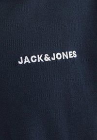 Marineblå stof med hvid broderet tekst, der står "JACK&JONES." Blød tekstur med en glat overflade og et enkelt, minimalistisk design.
