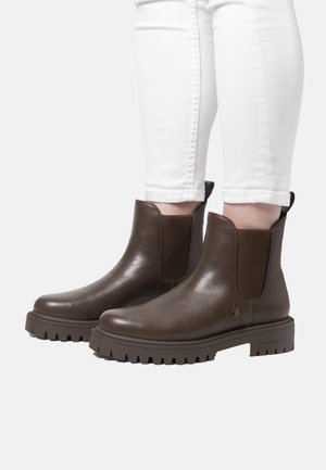 Bruna läderankelstövlar med elastiska sidopaneler och texturerade gummisålar, med ett guldfärgat logotypaccent på utsidan.