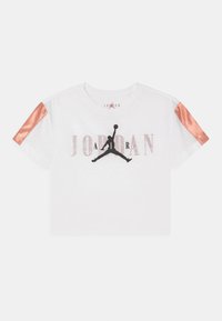 Biała, skrócona koszulka Jordan z czarnym logo Jumpman, wybledłym napisem "JORDAN" oraz błyszczącymi pomarańczowymi paskami na rękawach.