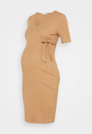 Robe de maternité à manches courtes, portefeuille, en tissu côtelé beige. Elle présente un détail noué à la taille et une silhouette ajustée qui s'adapte au ventre qui s'arrondit.