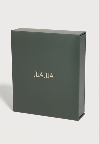 Σκούρο πράσινο ορθογώνιο κουτί που στέκεται όρθιο με το «JIA JIA» τυπωμένο σε χρυσό, στο κέντρο της μπροστινής όψης, σε απλό λευκό φόντο.
