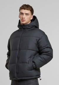 Sort pufferjakke med hætte, med lynlås lukning, elastiske manchetter og et quiltet design. Glat tekstur og et let udseende.
