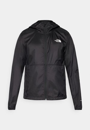 Crna lagana jakna od najlona, s patentnim zatvaračem, kapuljačom i elastičnim manžetama. Na prednjem dijelu se nalazi mali bijeli logo na lijevoj strani prsnog koša.