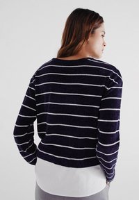 Námořnický modrý a bílý proužkovaný pletený svetr s kulatým výstřihem a dlouhými rukávy. Materiál má jemnou texturu a zkrácený střih.