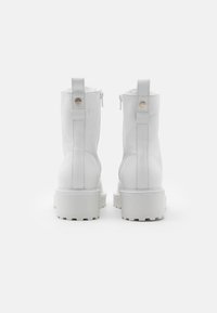 Weiße Leder-Ankle-Boots mit einer robusten Profilsohle. Mit einem Reißverschluss hinten und einer Lasche für einfaches An- und Ausziehen. Glatte Textur und minimale Designmerkmale.