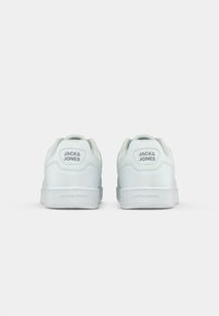 White leather sneakers with a smooth texture, rounded shape, and rubber sole. Features a hexagonal heel tab embossed with "JACK & JONES."