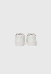 White leather sneakers with a smooth texture, round toe, and minimalistic design; features a low-top silhouette and cushioned sole.