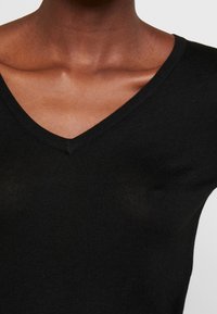 Czarny sweter z dekoltem w serek, wykonany z prążkowanego dzianiny. Dopasowany krój z gładką teksturą i wyraźnym dekoltem. Minimalistyczny design.