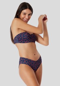 Bikini-set met een marineblauwe basis en rode bloemenpatronen. De top is strapless met een geraffineerd ontwerp; de onderkant heeft een high-waisted, curvy vorm.
