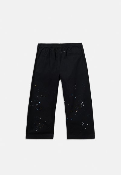 Μαύροι φαρδιοί παντελόνες με ελαστική μέση και πολύχρωμες πιτσιλιές μπογιάς, με μία μόνο πίσω τσέπη σε λευκό φόντο.