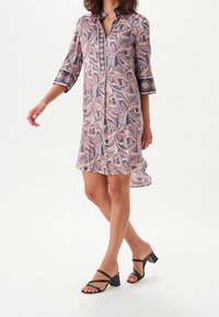 Sukienka na guziki z różowo-fioletowym wzorem liści, rękawy 3/4, zaokrąglony dół, lekka tkanina. W połączeniu z czarnymi sandałami na klockowym obcasie.