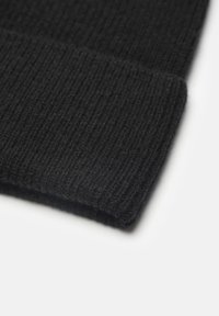 Czarna dziana czapka z prążkowanym wzorem i zawiniętym brzegiem. Materiał wydaje się gruby i miękki, odpowiedni na zimną pogodę.