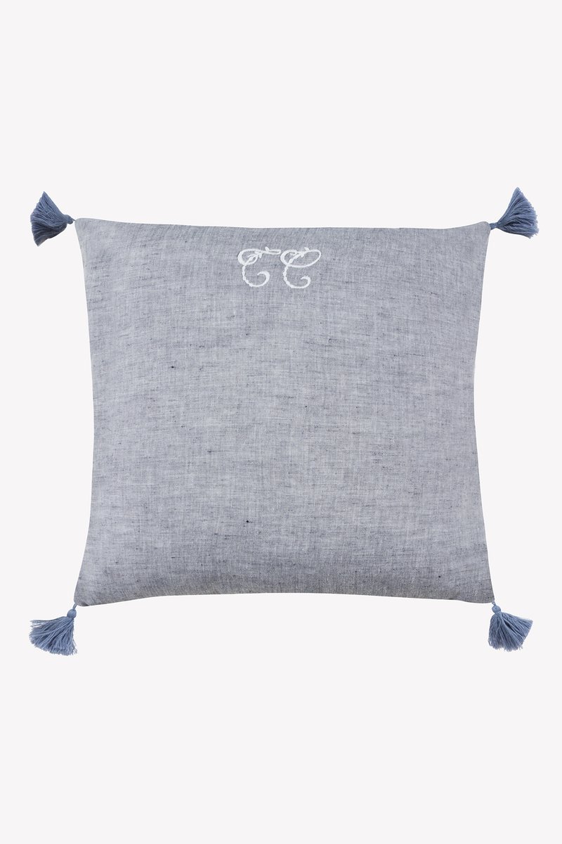 Μπλε υφαντό μαξιλάρι με διακοσμητικές φούντες σε κάθε γωνία, με κεντητό σχέδιο σε ανοιχτότερο μπλε χρώμα. Ομαλή υφή.