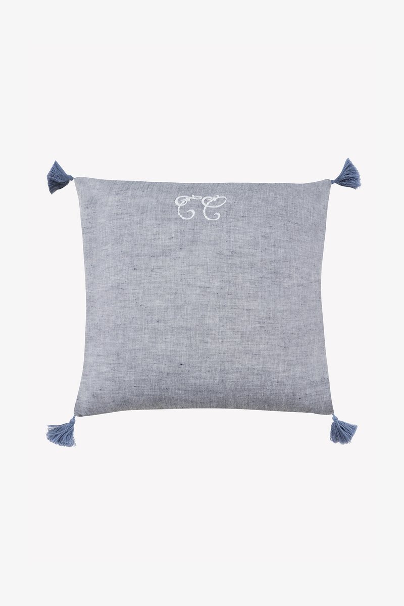 Μπλε υφαντό μαξιλάρι με διακοσμητικές φούντες σε κάθε γωνία, με κεντητό σχέδιο σε ανοιχτότερο μπλε χρώμα. Ομαλή υφή.