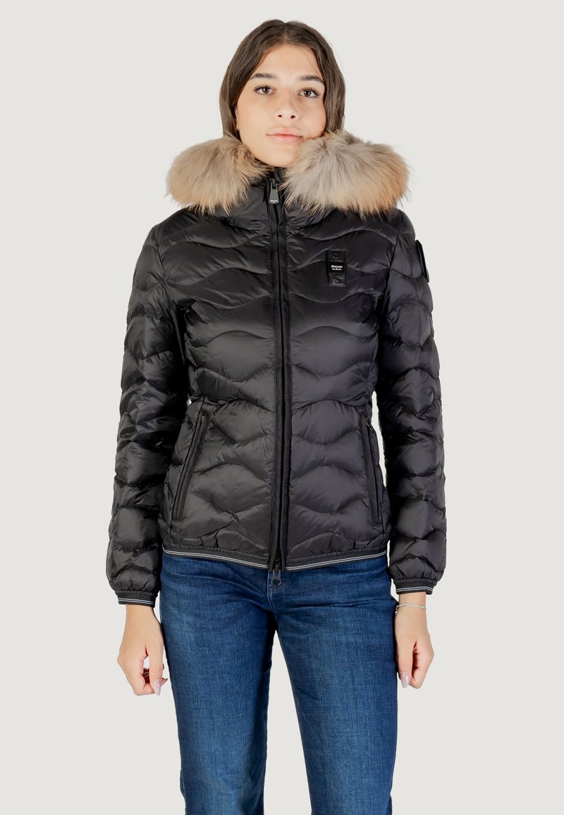 Zwarte pufferjack met geborduurd ontwerp, met een met bont gevoerde capuchon, ritsluiting en aansluitende taille. Gepaard met blauwe jeans.