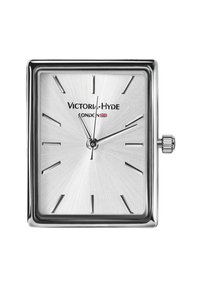 Reloj cuadrado plateado con esfera plateada cepillada, marcadores horarios angulares y manecillas delgadas. Incluye texto de la marca y una corona en el lateral.