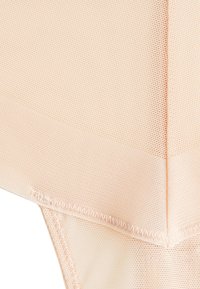 Tissu couleur pêche avec un motif en maille texturée, présentant des coutures lisses et des sections contrastantes. Conçu pour un ajustement près du corps, matière légère.