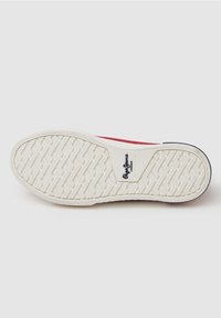 Weiße Gummisohle mit strukturiertem Fischgrätmuster, mit einem blauen Logo-Akzent und roten seitlichen Details.