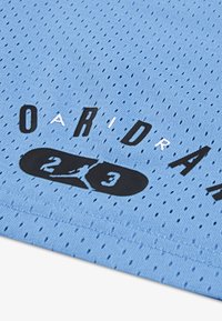 Υφασμα από ανοιχτό μπλε πλέγμα με μαύρα γράμματα. Περιλαμβάνει λογότυπα "AIR" και "23". Υφή με μικρές οπές σε όλη την επιφάνεια.