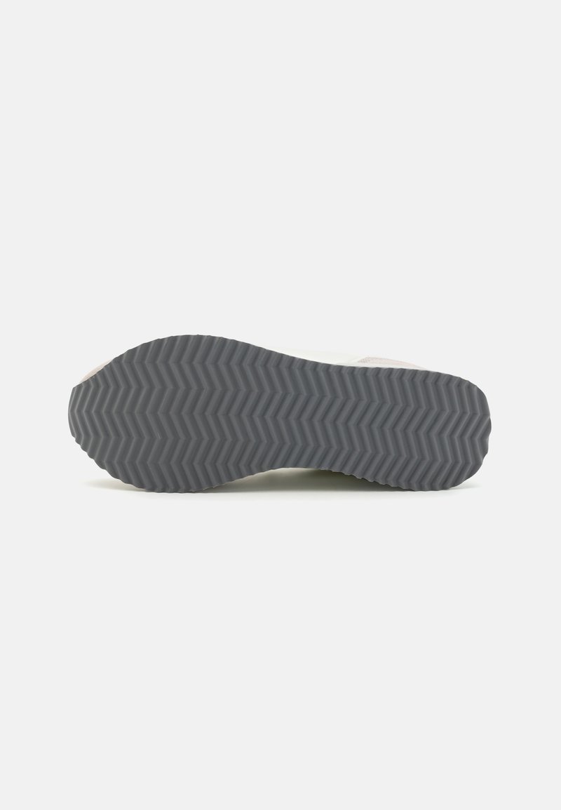 Suela de zapatilla en goma gris con un patrón de zigzag, que presenta una ligera curvatura en los bordes y elementos de diseño minimalistas.
