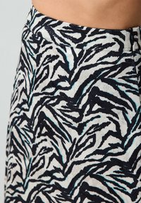 Zebra-muster Rock mit einem strukturierten schwarz-weißen Design, das Akzente in hellblau aufweist. Hergestellt aus weichem, flexiblen Stoff.