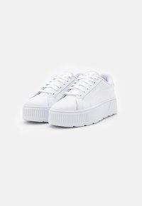Baskets en cuir blanc avec un bout rond, une épaisse semelle blanche, des détails texturés au niveau du talon et un design classique à lacets.