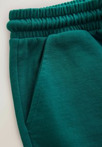 Sinistrohelbed dressipüksid on varustatud soonilise elastse vöökohaga, siledast puuvillast materjalist ning praktilise küljetaskuga.