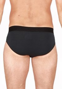 Slip da uomo a strisce nere con un elastico nero solido in vita, con il nome del marchio discretamente impresso. Texture liscia.