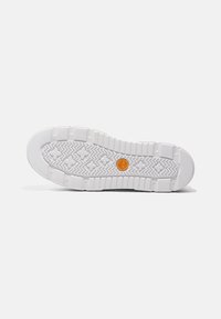 Hvite sneakersåler med teksturert gummi med fiskebeinmønster og en sirkulær oransje logo i midten.
