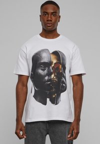 Valge puuvillane t-särk, millel on graafiline trükk kattuvatest inim- ja koljupiltidest tumedates ja metallsetes toonides. Lühikesed varrukad, ümar kaelus.