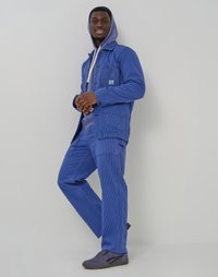 Blue corduroy jacket with chest pockets over a gray hoodie and matching blue corduroy pants. Worn with gray shoes featuring black accents.