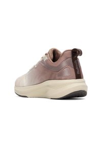 Zapatilla deportiva con un upper en rosa claro y beige con textura de malla, un collar acolchado y una entresuela crema con una suela exterior de goma negra.