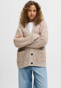 Beżowy sweter z kolorowymi wtrąceniami, z długimi rękawami, dwiema przednimi kieszeniami, dekoltem w kształcie litery V oraz czarnymi guzikami.