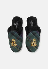 Green plaid slippers featuring a black faux fur lining, gold embroidered initials, and a crown emblem on a textured surface.