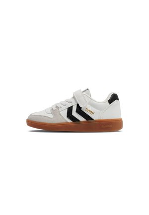 Zapatilla blanca con suela de goma, rayas en zigzag negras en el lateral, puntera de ante gris y una sola tira de velcro sobre los cordones.