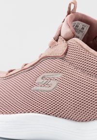Růžová sportovní obuv zSíťoviny se stříbrnými detaily, zaoblený tvar, texturovaný povrch a bílá podrážka. Obsahuje smyčku na zadní straně pro snadné obouvání.