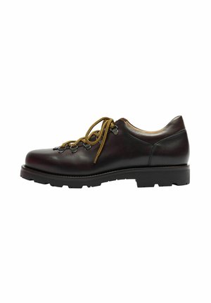 Zapato de cuero marrón con una textura suave, puntera redonda y cordones amarillos en contraste. Suela de goma negra gruesa con un patrón texturizado.