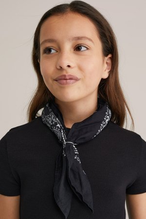 Melnā kokvilnas šalle ar baltu paisley rakstu, sasieta ap kaklu. Valkāta kopā ar pieguļošu melnu ribotu īsām piedurknēm topu.