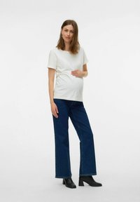 Maternitātes T-kreklis mīkstā baltā audumā, īsām piedurknēm; apvienots ar tumši zilajiem plašajiem biksēm un melniem zābakiem ar papēdi. Vienkāršs dizains, bez rakstiem.